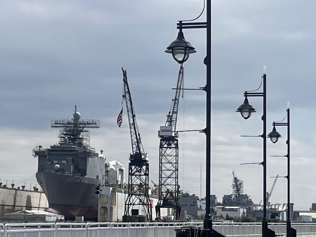 US Navy vessel under maintenance at a Hampton Roads shipyard with dock cranes