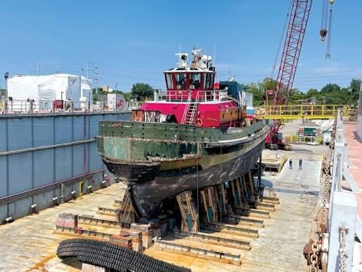 Red tugboat in dry dock at a Hampton Roads shipyard undergoing hull repair